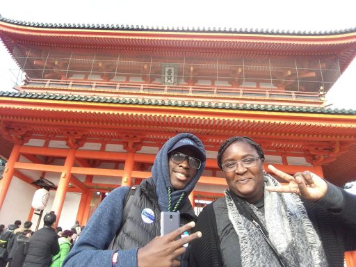 Deux personnes souriantes en devant d'un bâtiment traditionnel japonais.
